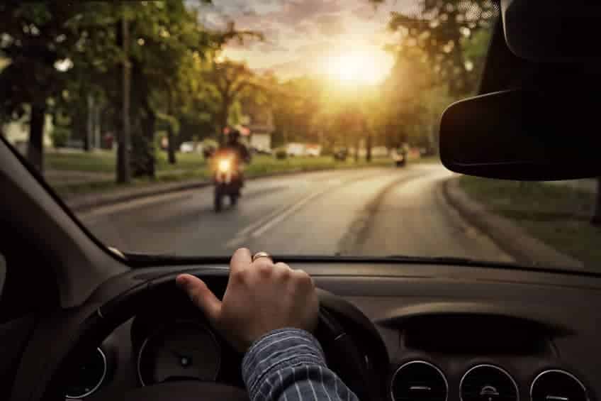 view from a driver of a car going towards a motorcyclist