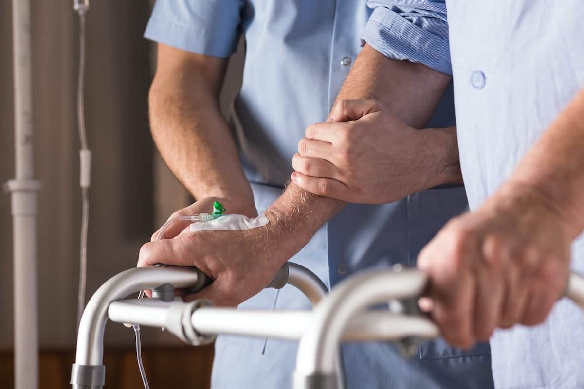 Nurse standing at elderly woman's bedside