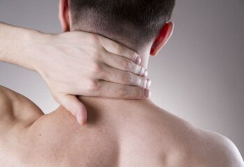 person holding the back of their neck in pain