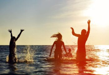 silhouettes of young group of people jumping in the ocean