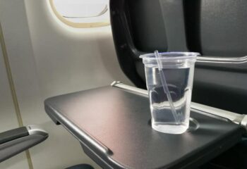 a cup of water sitting on a tray table in an airplane