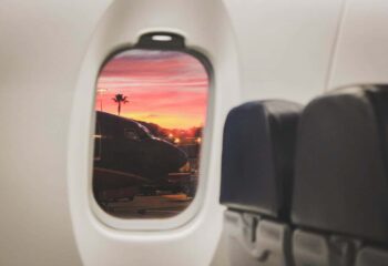 the view from a passenger's perspective looking out the window of an airplane at another plane and a sunset in the background