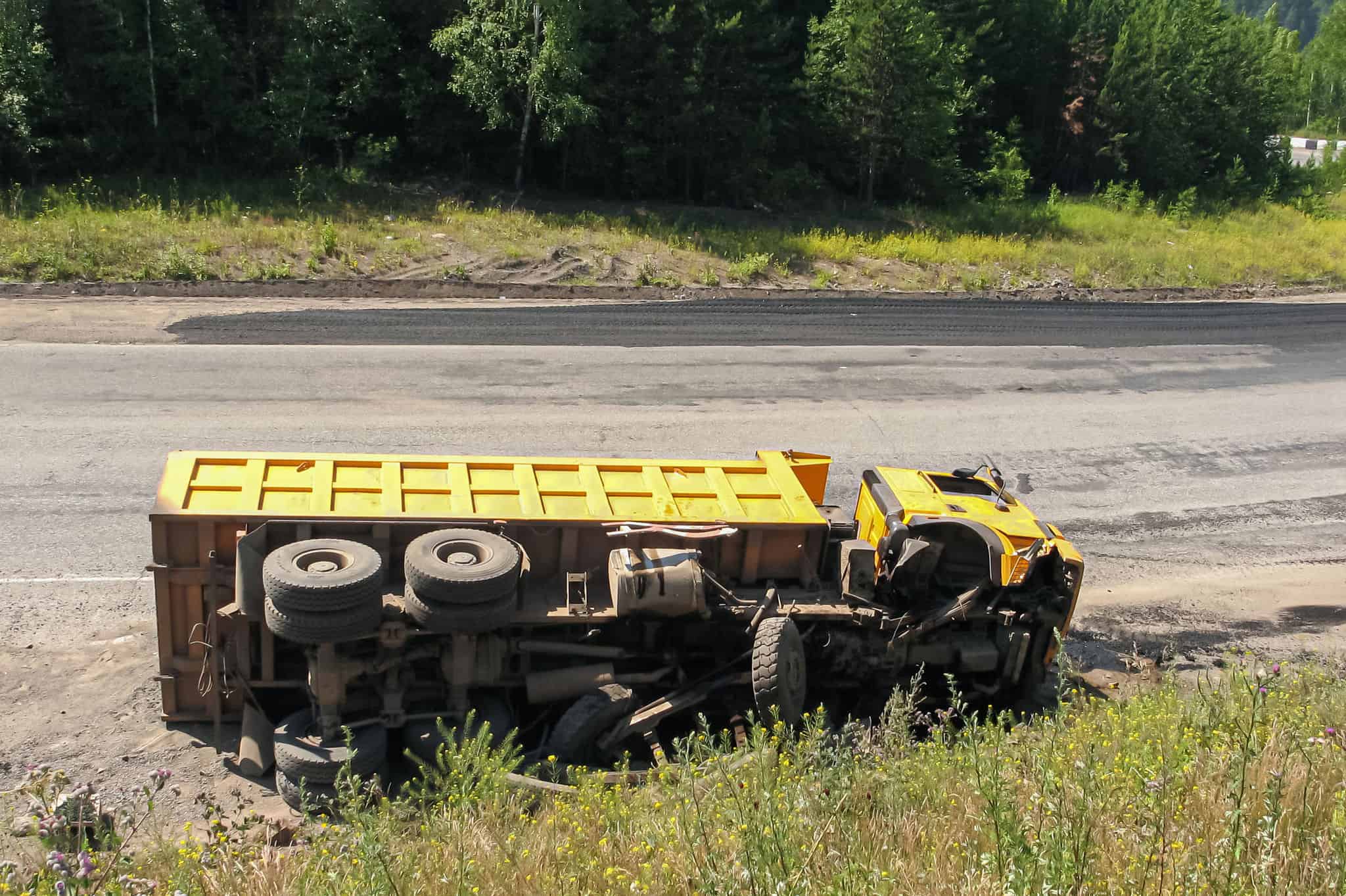 An overturned truck on an highway in an accident. Crashed dump truck on a road.
