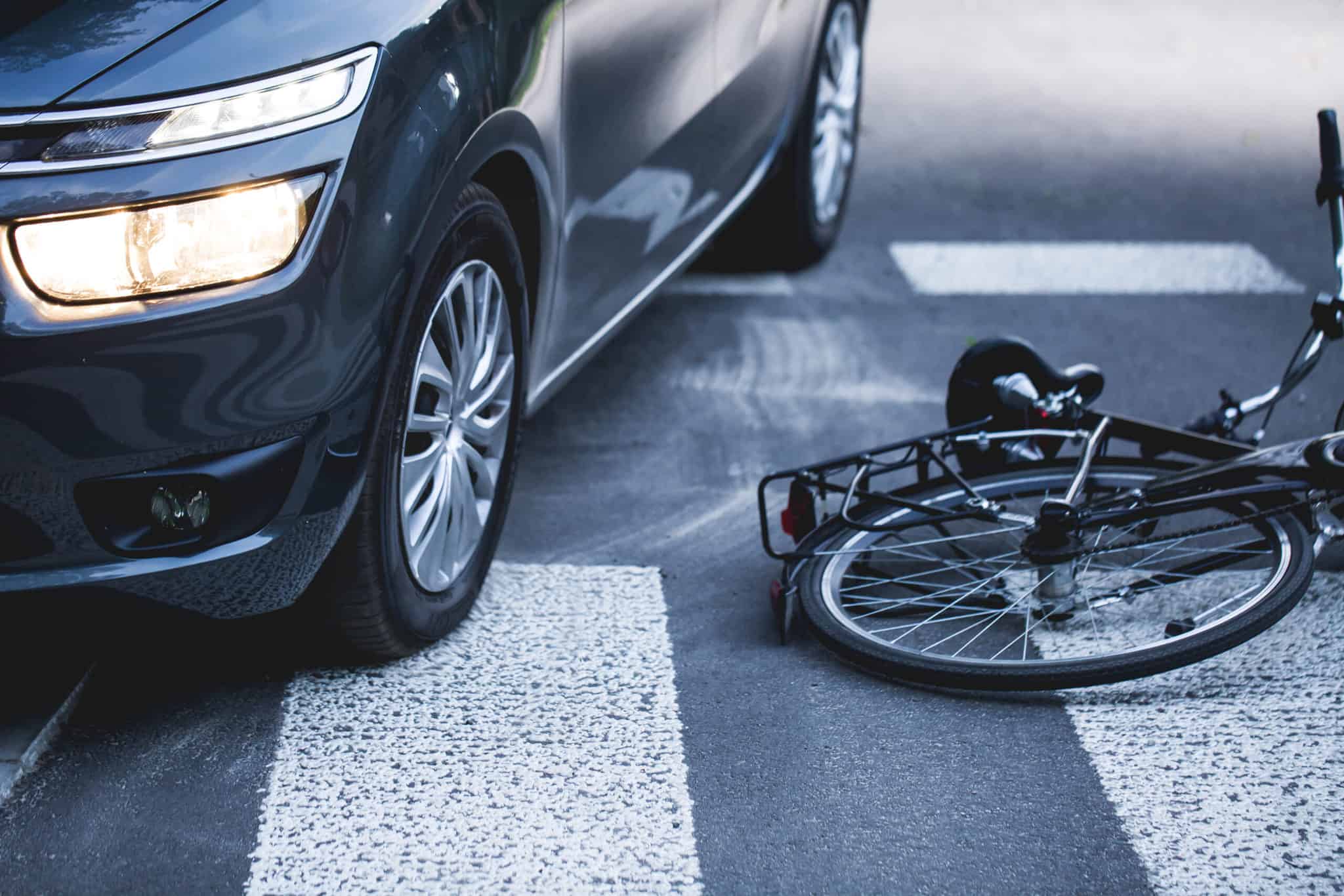 Car stopped in the crosswalk next to a downed bicycle after a bike accident